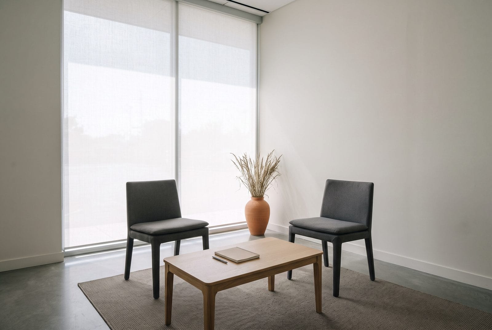 A small consultation room with two plain chairs either side of a low pale table.