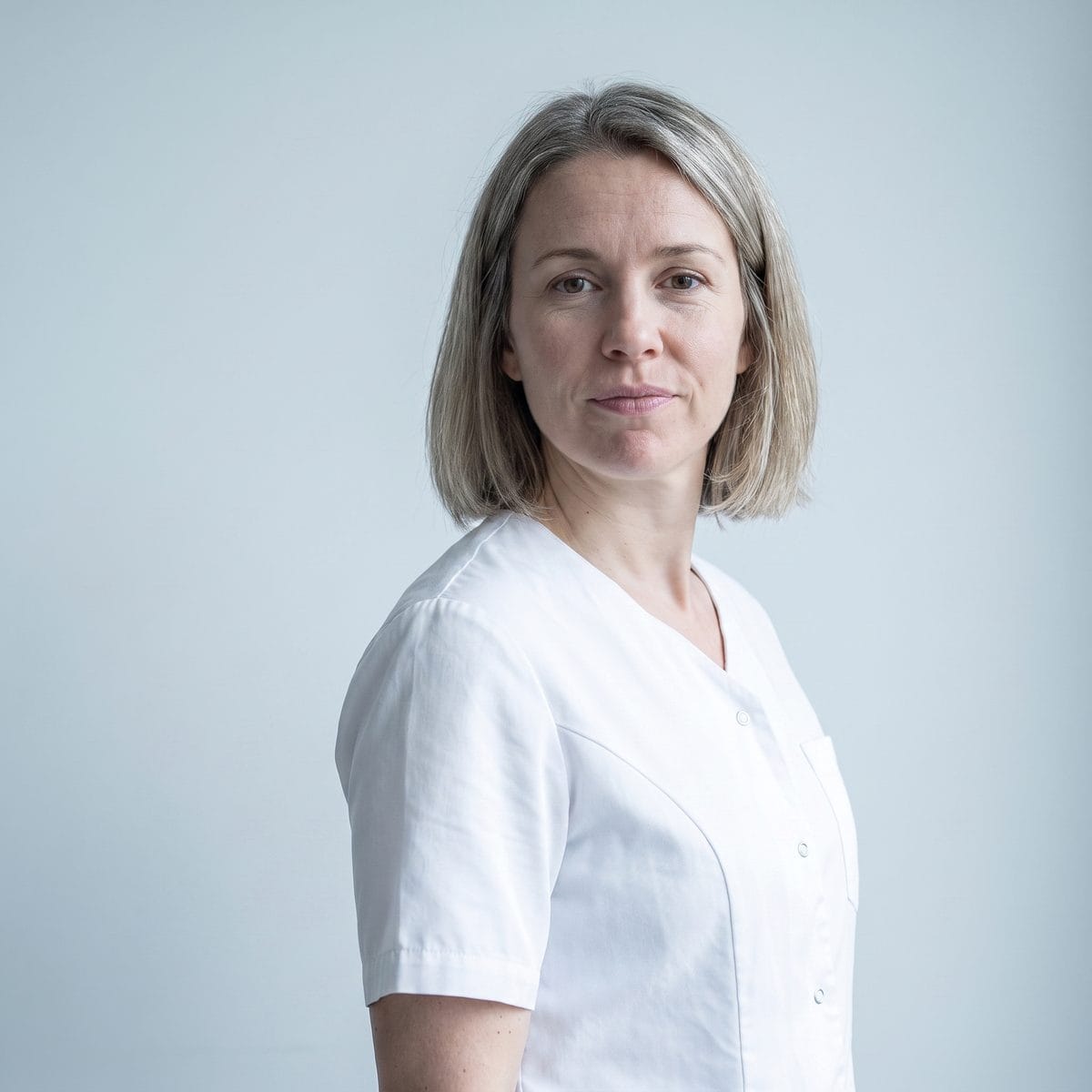 Portrait of the practice's patient care coordinator against a plain pale background.